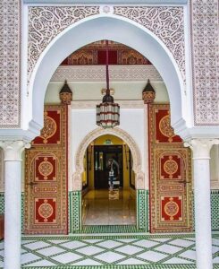 Traditional Moroccan architecture with ornate arch, colorful zellige tiles, and detailed patterns in Marrakech showcasing Islamic design and cultural heritage.