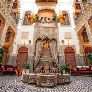 Traditional Moroccan riad interior with fountain, zellige tiles, carved wood, and elegant design in Marrakech